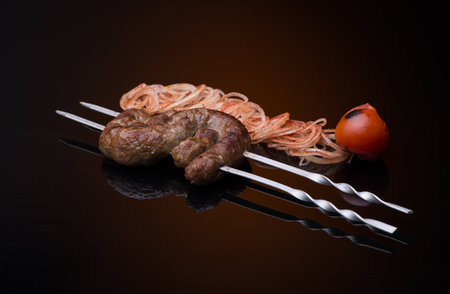 kebab sticks on skewers with onion and tomato on dark backgroundの写真素材