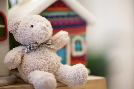soft white teddy bear on the shelf in the background a small houseの写真素材