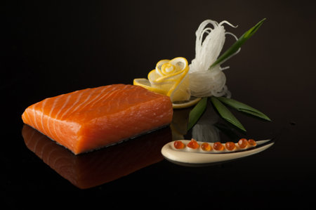 piece of sushi with lemon and leaf on a dark background with reflectionの写真素材