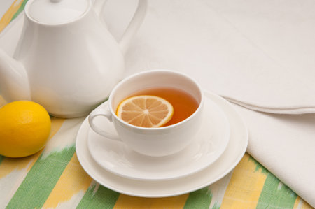 on a napkin cup of tea with lemon in a saucer and teapotの写真素材