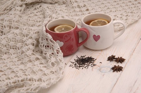 two cups of tea with lemon and scarf on wooden boardsの写真素材