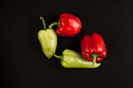 fresh red bell pepper and green close-up on a black background