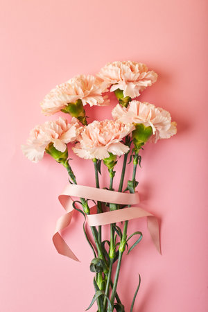 Bouquet of pink carnations. Design concept of holiday greeting with carnation bouquet on pink table background.の写真素材