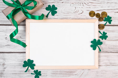 Happy St. Patrick's Day concept. Clover shamrock, gold coins and gift with green ribbon on white background. Festive composition. Place for text.の写真素材