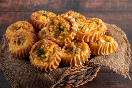 Basket with fresh muffins on a wooden background. Homemade cakes with vegetables and cheese. Recipe...