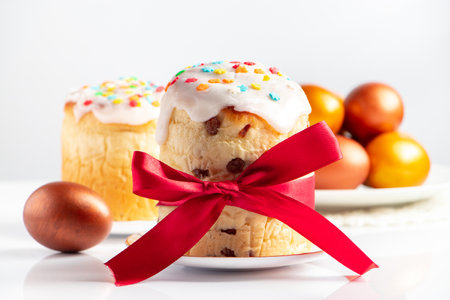 Easter cake panettone with sweet icing and golden eggs on white plate. Happy spring holiday.