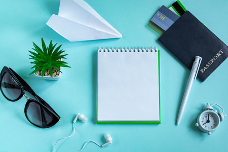 Flatlay travel accessories on a blue background. Summer vacation concept. Passport, credit cards, sunglasses, headphones, and a traveler's notebook. Copy space.の写真素材