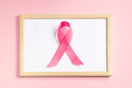 Pink ribbon on colored background. Breast Cancer Awareness Month symbol. Women's health care concept. Promotion of campaign to fight cancer. Copy space.の写真素材