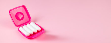 Tampons in pink box. Feminine hygiene products on pastel background. Menstruation and womens health concept. Banner format.の写真素材