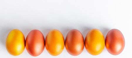 Shiny golden Easter eggs close-up on a white background. Place for text, banner formatの写真素材