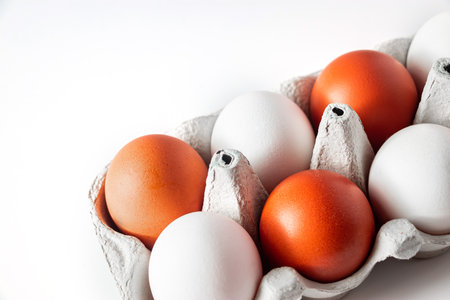 Raw white and brown chicken eggs in eco-friendly cardboard box on light background. Farm product,...