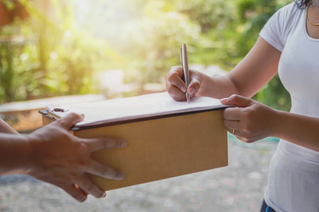 The woman is signing the documents the delivery staff gave To confirm parcel receipt - delivery service conceptの写真素材