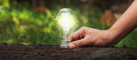 Holding a light bulb on the ground Energy saving conceptの写真素材