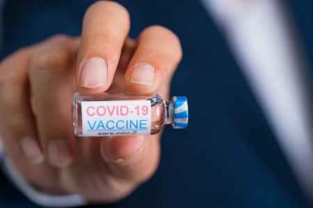 Focus select and blur Foreground Vaccine COVID-19 corona virus and syringe on hand business man in...