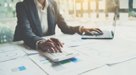 Accountant working on desk using calculator for calculate finance report in office.の写真素材