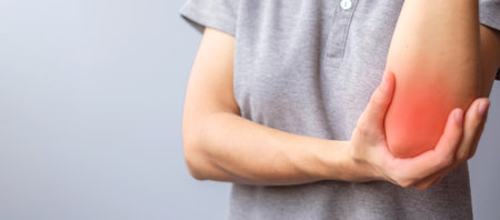 adult female with her muscle pain on gray background. Woman having elbow ache due to lateral epicondylitis or tennis elbow. injuries and medical conceptの写真素材