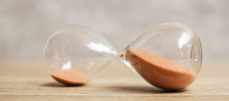 Hourglass on table, Sand flowing through the bulb of Sandglass measuring the passing time. countdown, deadline, Life time and Retirement conceptの写真素材