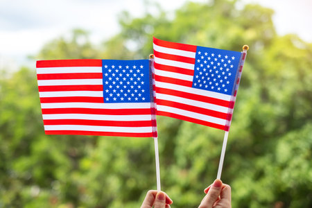 hand holding United States of America flag on green background. USA holiday of Veterans, Memorial, Independence ( Fourth of July) and Labor Day conceptの写真素材