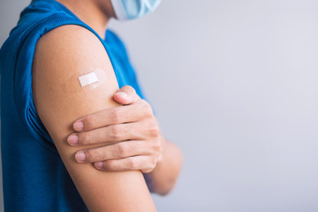 Happy man showing his arm with bandage after receiving vaccine. Vaccination, immunization, inoculation and Coronavirus ( Covid-19 ) pandemicの写真素材