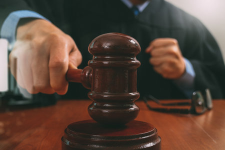 justice and law concept.Male judge in a courtroom striking the gavel,working with digital tablet...