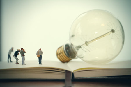 Creative idea concept - miniature photographer with vintage light bulb on open paper notebookの写真素材