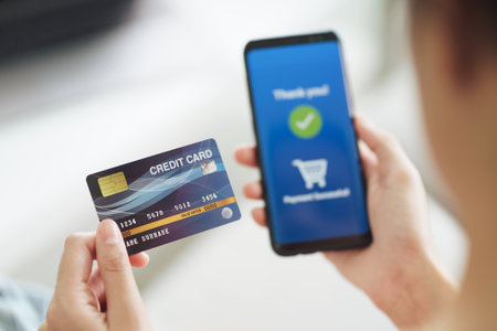 Young woman holding credit card and using smart phone for online shopping, internet banking,...