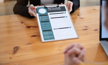 Close up people hands on a wooden table, boss and woman during interview. Director hr manager holding resume paper,  woman talking about yourself. HR recruitment and hiring conceptの写真素材