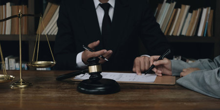 Business woman and lawyers discussing contract papers with brass scale on wooden desk in office....