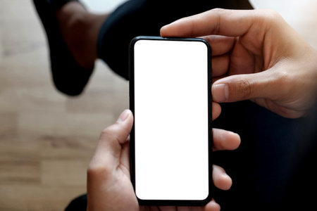 Cropped shot top view of businessman hands using smartphone mockup at the white office desk. Blank...