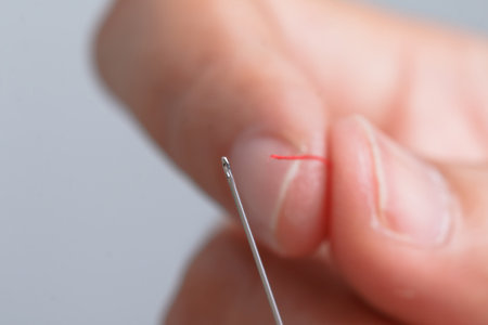 Close up hand holding the red threaded with stitching needles. Select focus shallow depth of field...