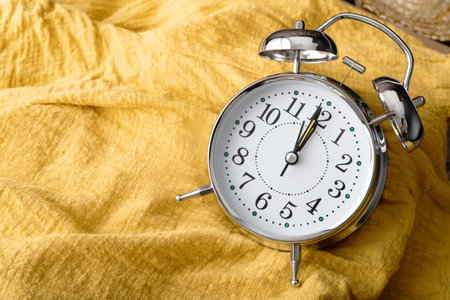 Close up the alarm clock place on the yellow fabric. Abstract background and texturd with the time.の写真素材