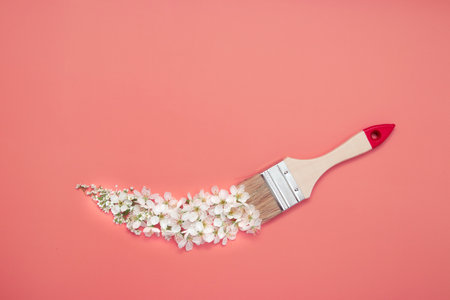 Brush with white flowers on color background. Spring magic creative concept with copy spaceの写真素材
