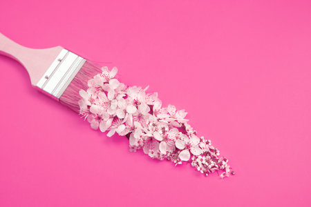 Brush with white flowers on pink background. Spring magic creative concept.