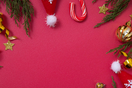 Christmas red background with decorative elements and green branches flat lay with copy space