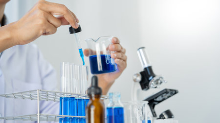 Scientist wear lab coat and protective wear are working with research or doing investigations with test tubes in experiment, Laboratory and development concept.の写真素材