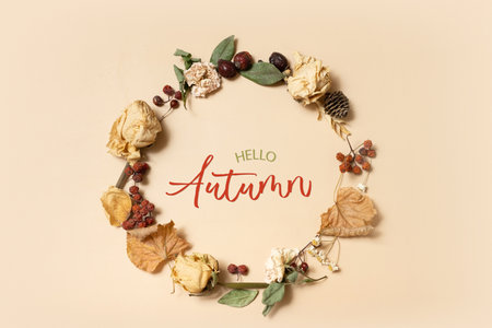Autumn composition with Hello Autumn text. Wreath made of dried leaves and flowers on pastel beige background. Flat lay, top view.の写真素材