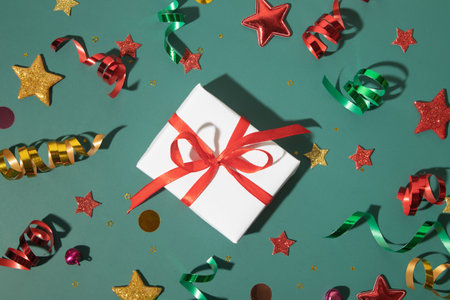 Top view shiny holiday background with gift box, stars, streamers, sparkles. Creative flat lay for...