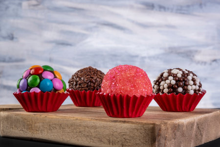 assorted brigadeiros on wooden board with multicolored background.