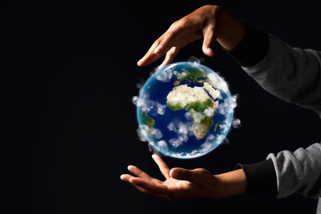 Environment concept. Earth in human hands on black background.の写真素材