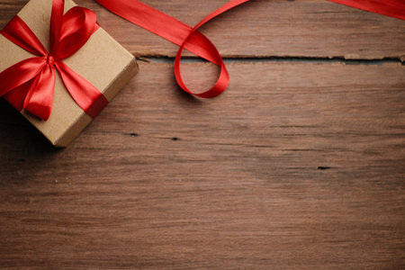 Selective focus of gift box with red ribbon and love shaped paper over rustic wooden table, top view flat lay.の写真素材