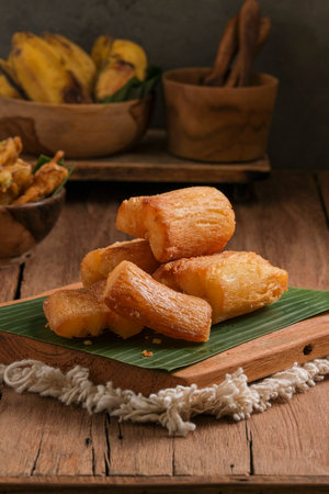 Fried cassava is served on a cutting board with a banana leaf base. Arranged in such a way with a classic kitchen table themeの写真素材