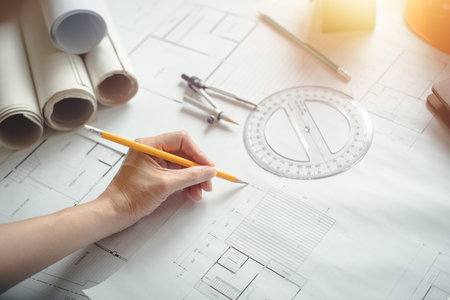 Hands of architect woman or engineer using pencil working with blueprint on desk in office....