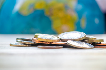 Coins stack on wood table in front of globe model. Concept for loan, property ladder, financial, mortgage, real estate investment, taxes and bonus.の写真素材