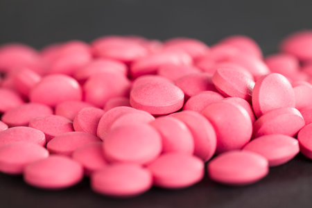 pink pile of unpacked pills lying on a black background close up of medical thingsの写真素材