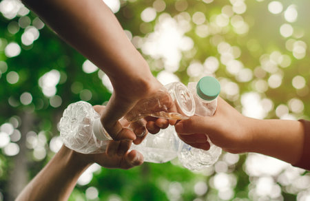 Removing waste to conserve a better world with good environment and natural atmosphere Hand in hand as a team, unity, holding plastic bottles together. reduce global warming save the worldの写真素材