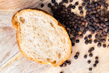 sliced baguette with spices, food made from flour, next to dried black pepper grains, which is used for cookingの写真素材