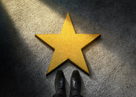 Success in Business or Personal Talent Concept. Top View of Businessman in Shiny Oxford Shoes standing in front of a Golden Star on the Dark Cement Floorの写真素材