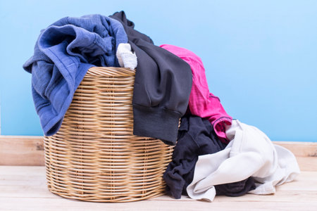 Clothes in a laundry wooden basket on wood table in the roomの写真素材