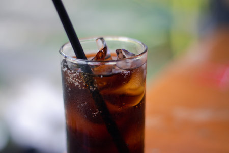 Close-up shot of a glass of cold cola. Soft drink, soft drink in a glass with ice on blurred background.の写真素材