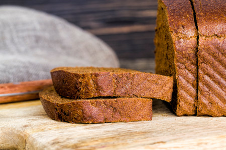 sliced black rye bread loaf, close up on the table, one